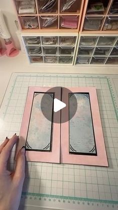 someone is cutting out an open book on a table with some scissors and tape in front of it