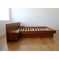 a bed that is in the middle of a wooden floor with drawers on each side