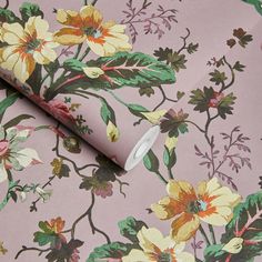 a pink floral wallpaper with green leaves and flowers on it's side, next to a roll of toilet paper