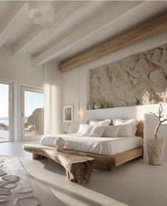 a large white bed sitting in a bedroom next to a wooden table and window sill