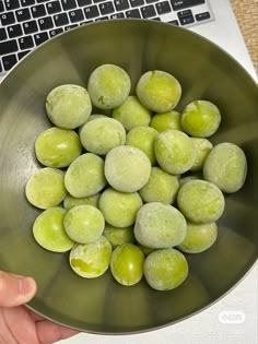 a bowl filled with green olives next to a laptop