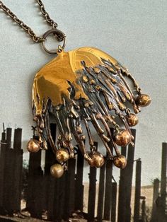 a gold and black necklace on a chain that is attached to a fence with beads