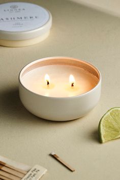 two candles sitting on top of a table next to a lime and matchsticks