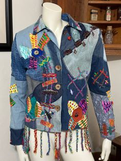 "Vintage 80's Sandy Starkman boho patch-worked denim jacket with embroideries and colorful appliqués. Shoulder pads. In excellent structural condition - a button is loose in the middle of the front flower, a closure button is missing - with so much going on with this awesome jacket, flaws are difficult to find. The fraying of the hanging braids at the bottom look like they're supposed to be that way. No stains or loose seams. Size M Chest: 21\" Length: 22\" not including braids See pictures I buy from estates sales, auctions, garage sales and thrift stores and do not claim to be an expert on any items. I try the best I can to describe the item as I see it. I test all items to the best of my ability. In some cases I may not be exactly sure how an item works, therefore; I will try to identif Patch Work Denim Jacket, Multicolor Denim Outerwear With Patches, Multicolor Patchwork Long Sleeve Denim Jacket, Multicolor Patchwork Cotton Denim Jacket, Multicolor Cotton Patchwork Denim Jacket, Hippie Patchwork Cotton Denim Jacket, Hippie Cotton Patchwork Denim Jacket, Hippie Patchwork Denim Jacket For Spring, Spring Hippie Patchwork Denim Jacket