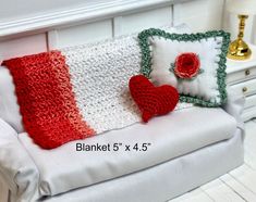 a white couch with red and green crocheted pillows on it's back