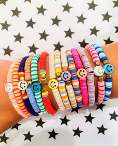 a woman's arm with bracelets and smiley face charms on it, all in different colors