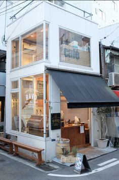 a white building with a black awning next to a street