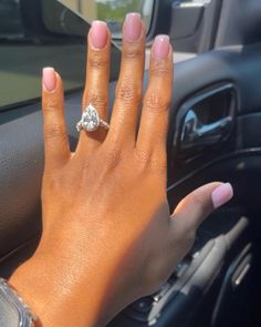 a woman's hand on the steering wheel of a car with a diamond ring