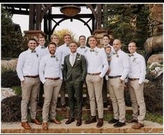 a group of men standing next to each other wearing white shirts and khaki pants