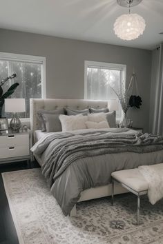 a large bed sitting in a bedroom next to two windows and a rug on the floor