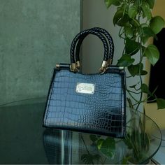 a blue handbag sitting on top of a glass table next to a potted plant