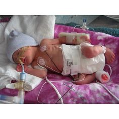 a baby is laying down with an iv in it's mouth and wearing a hat