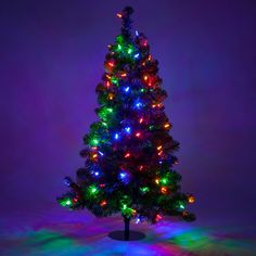 a brightly lit christmas tree in front of a purple background