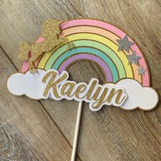 a cake topper that says kaleyn with a rainbow and stars on it