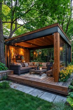 an outdoor living area with couches and tables in the middle of it, surrounded by trees