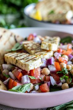 a salad with tofu, chickpeas and spinach in a pink bowl