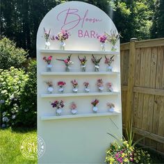 a sign that has flowers on it in front of a fence and some plants behind it