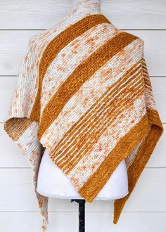 an orange and white striped knitted shawl on a mannequin head stand