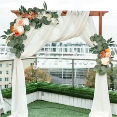 an outdoor ceremony setup with flowers and greenery on top of a roof in the city