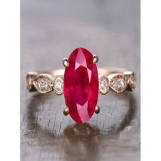 an oval shaped ruby and diamond ring on a wooden surface