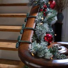 a christmas tree with ornaments and lights on it in front of some stairs at home