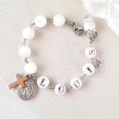 This stunning Baptism bracelet is a truly divine piece that combines elegance and spiritual significance. Crafted with natural mother of pearl beads, it features gold plated virgin Mary and cross charms that symbolize protection and faith. The bracelet is personalized with a handcrafted initial letter, adding a unique touch to this meaningful piece. Perfect for commemorating a special occasion or as a thoughtful gift, this bracelet is a beautiful reminder of faith and blessings. *MATCHING ROSARY PRAYER: https://www.etsy.com/au/listing/1492666531/personalized-rosary-beads-pearl-rosary *Materials:  High Quality 18k gold plated Stainless Steel charms * Gemstone: Genuine mother of pearl beads, round shape, 6mm * Closure: adjustable finial, lobster clasp * Letter beads: handmade, mother of pear Elegant White Name Bracelet For Gift, White Engraved Bracelets For Weddings, Spiritual White Mother Of Pearl Jewelry, Hypoallergenic White Jewelry For Baptism, Elegant Personalized Rosary Bracelet With Round Beads, Adjustable Silver Pearl Bracelet For Baptism, Elegant White Name Bracelet For Mother's Day, Adjustable Mother Of Pearl Bracelet As Gift, Personalized White Charm Bracelet For Birthday