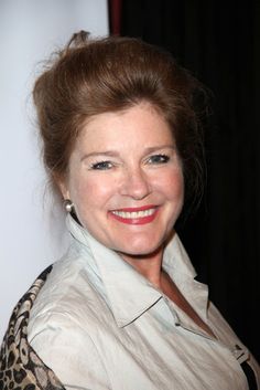 a smiling woman wearing a white shirt and leopard print jacket