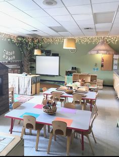 a classroom with tables, chairs and a projector screen