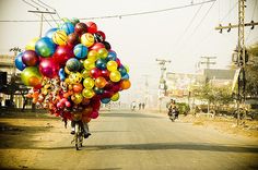 a person riding a bike down a street with balloons attached to it's back