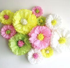 colorful paper flowers are arranged on a white surface