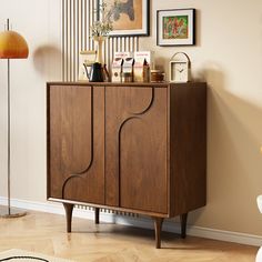 a wooden cabinet in the corner of a room with pictures on the wall behind it