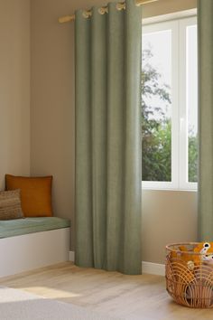 a window with green curtains and a basket on the floor