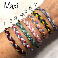 several different colored braided bracelets on someone's arm