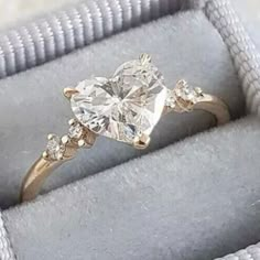 an engagement ring in a box with diamonds on the sides and gold accents around the band