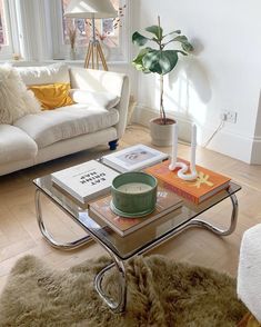 a living room with a glass coffee table in the middle and a white couch behind it