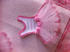 a pink and white baby's first birthday dress on top of a bed sheet