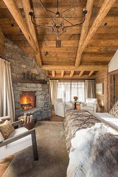 a rustic bedroom with stone fireplace and wood ceiling