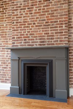 an empty fireplace with a brick wall in the background