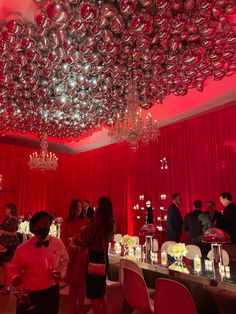 a group of people standing in front of a table with silver balls hanging from the ceiling