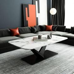 a modern living room with grey couches and orange pillows on the wall, black furniture