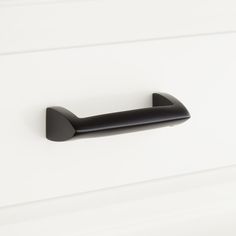 a black door handle on a white cabinet