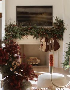 stockings hanging from the mantle in front of a fireplace with christmas decorations and greenery