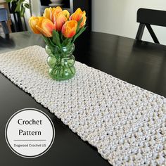 a crocheted table runner with flowers in a vase