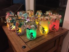 several jars with fairy lights in them sitting on a wooden table next to a window