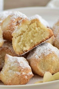 a white plate topped with powdered sugar covered pastries