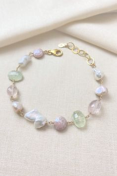 This handcrafted bracelet showcases a gentle mix of gemstones and pearls. It features ultra baroque white and mauve pink pearls that glow alongside faceted rose quartz and peach mystic moonstone. A touch of contrast is added by the spring green prehnite in this artisanal piece. Bracelet length: 8-9 inches (can be shortened on request) Materials: gold fill, freshwater pearls, rose quartz, mystic moonstone, prehnite Gift box included. Free shipping on US orders 30-day free returns Our artisan gems Elegant Adjustable Pastel Bracelets, Elegant Handmade Pastel Jewelry, Elegant Pastel Bracelets As Gift, Elegant Pastel Bracelets For Gifts, Multi Gemstone Bracelet, Pink Pearls, Gemstone Beads Jewelry, Handcrafted Bracelets, Mauve Pink