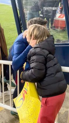 two children are standing on the side of a bus looking at something in front of them