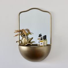 a mirror sitting on top of a shelf next to a vase with flowers in it