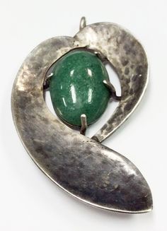 a silver pendant with a green stone in the center