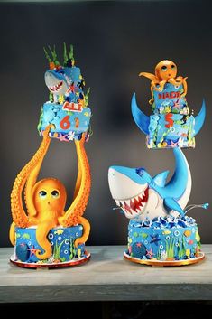 three cakes decorated to look like animals and fish with numbers on them, sitting on a table